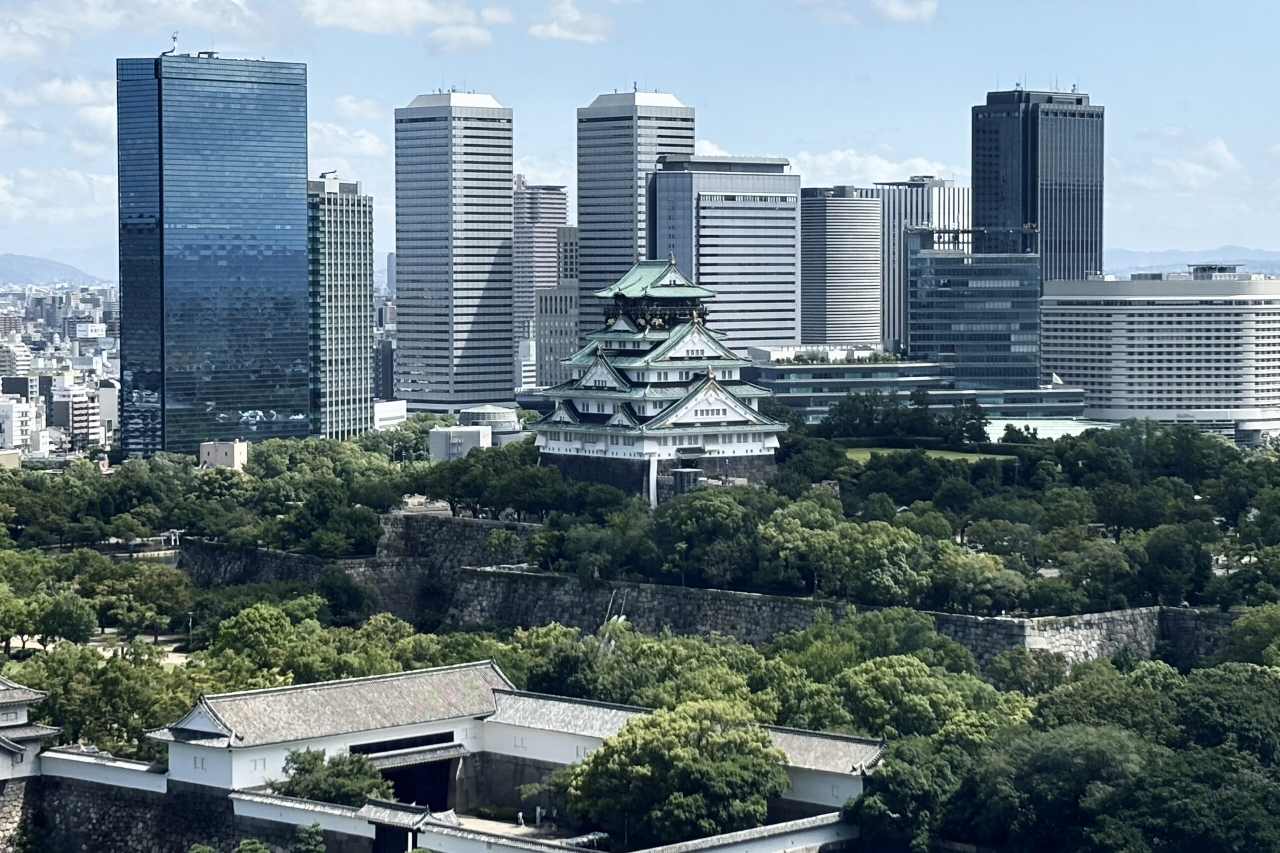 大阪城天守閣與護城河外圍石牆，後方為大阪商務園區高樓