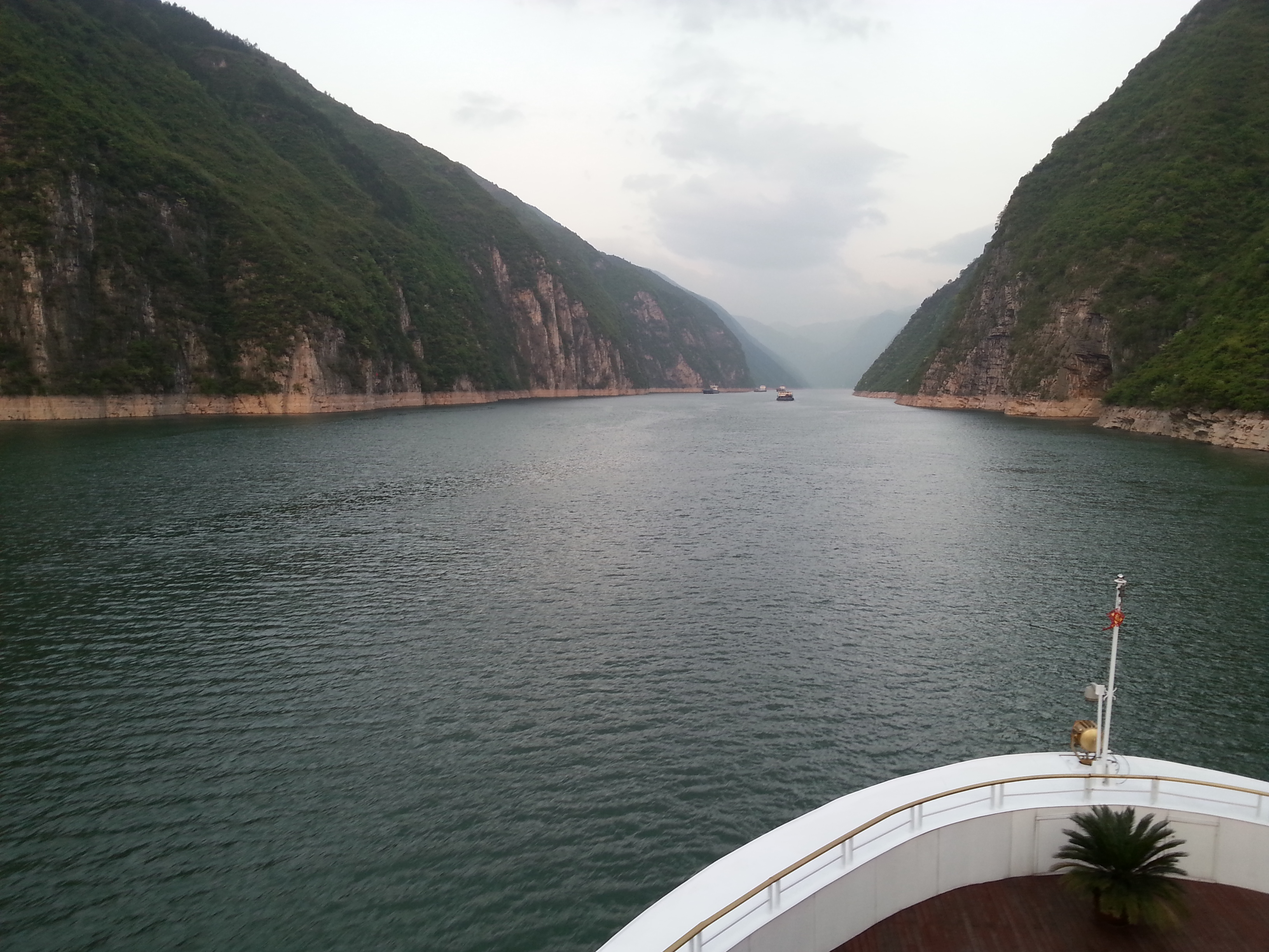 實拍長江巫峽水道與兩岸山勢，前景可見河輪船頭